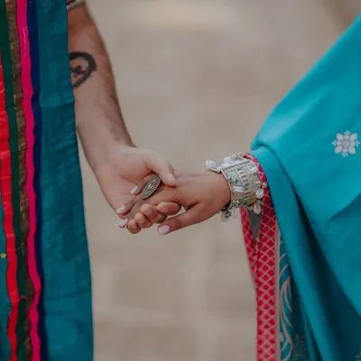 A close-up on the hands, symbolizing the divine and eternal connection of Radha and Krishna. The traditional attire and jewelry add to the authenticity of this themed pre-wedding shoot.