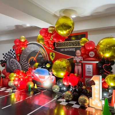 A complete Ferrari-themed first birthday stage with a race track floor, light-up number "1", and a personalized backdrop.