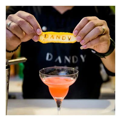 A showcase of our collaboration with Dandy - The Fio Bar. Here, a mixologist adds a custom-branded garnish to a vibrant pink cocktail, demonstrating our flair for personalized beverage experiences.
