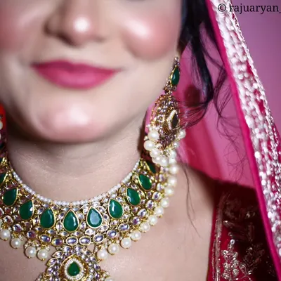 A close-up detail shot focusing on a bride's stunning emerald and pearl necklace. This type of macro photography highlights the intricate details that complete the bridal look.