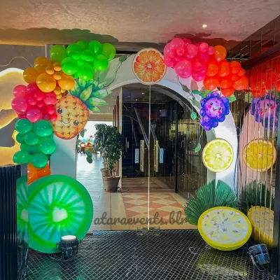 Welcome your guests with a burst of color! This fruit-themed balloon arch, complete with smiling pineapple and citrus cutouts, sets a fun and festive tone right from the entrance.