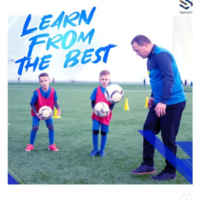 Learning from the best is non-negotiable here. An instructor demonstrates proper technique to two young players, ensuring they understand the fine details of ball handling and control from the very beginning of their football education.