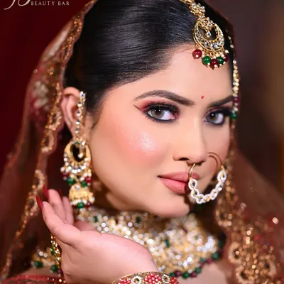A close-up of a classic Indian bridal look. I've used a winged eyeliner and red tones on the lower lash line to define the eyes, complemented by a flawless base and heavy traditional jewelry for a complete wedding day look.