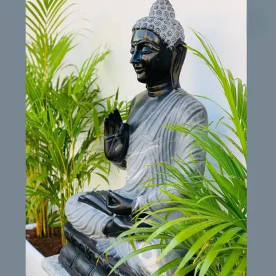 A close-up of a tranquil garden feature. We placed this beautiful grey marble Buddha statue amidst lush Areca Palms to create a focal point of peace and serenity in a tropical-themed garden.