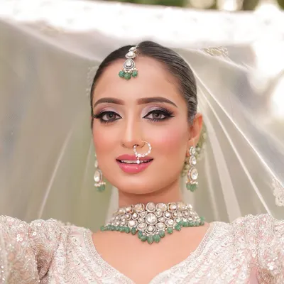 A breathtaking close-up of our modern bride. I created a sharp, defined eye with a subtle shimmer and a soft pink lip to complement her white lehenga and emerald jewelry.