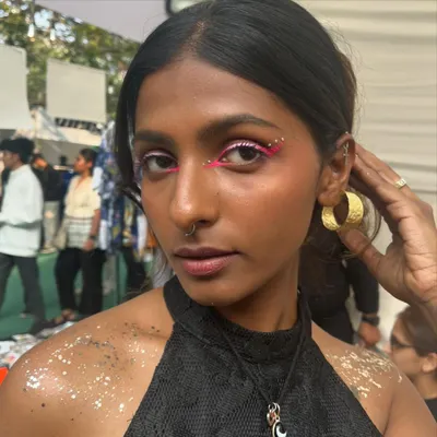 A fun and creative look from the Under25 Summit. This features a bold pink graphic liner with rhinestones and body glitter.