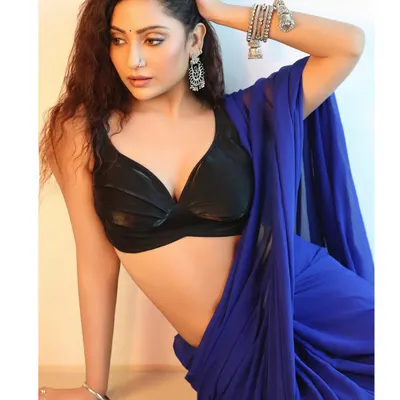 A modern interpretation of a saree look, pairing a vibrant blue saree with a stylish black bralette. The pose is relaxed yet elegant, perfect for a contemporary fashion portfolio.