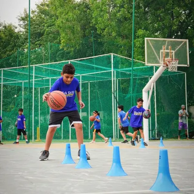 A young player practices dribbling around cones, a fundamental drill for improving ball control and agility. We teach kids to navigate tight spaces, which is a crucial skill for moving past defenders in a real game.