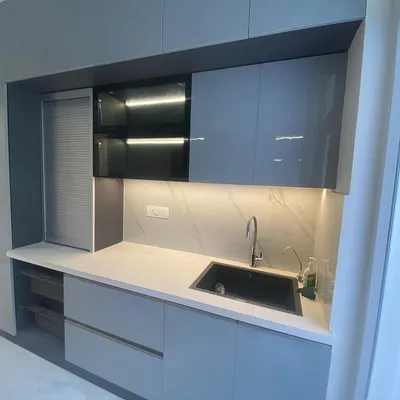 This sleek, grey modular kitchen features handleless cabinets and built-in appliances for a clean, minimalist look. The under-cabinet lighting provides excellent task lighting.