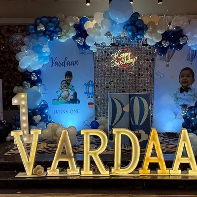 A classic blue and white hot air balloon and teddy bear theme for Vardaan's first birthday. The stage features custom backdrops, a silver sequin panel, and a beautiful balloon arch.