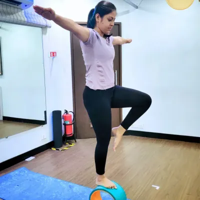 The yoga wheel is a fantastic tool for challenging your balance. Here, a student practices a standing balancing pose on the wheel, engaging her core and finding a point of focus to remain steady.