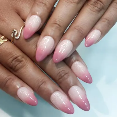 A classic pink and white ombre on elegant, pointed almond nails. The seamless blend and subtle glitter finish create a look of pure sophistication.