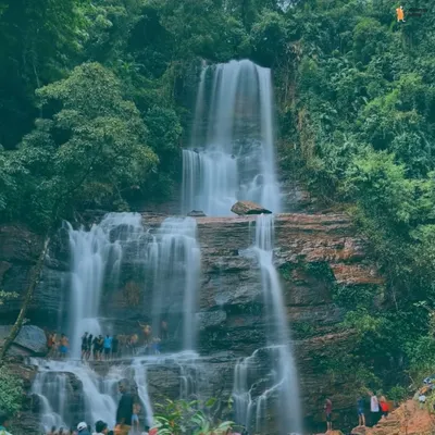 A majestic, multi-tiered waterfall in Chikmagalur, with our group visible at the base. This shot captures the scale and power of the waterfalls we visit.