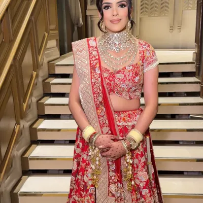 A full-length view of a radiant bride in her stunning red floral lehenga. The makeup is balanced to complement the intricate outfit, ensuring she looks breathtaking from every angle.