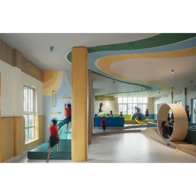 Another view of the soft-gym, a space designed for active bodies and curious minds. The undulating landscape, climbing wall, and rolling wheel provide endless opportunities for physical challenges and imaginative play.