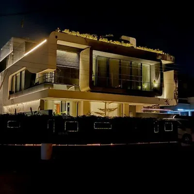 This full view of a modern residence in Panchkula demonstrates how linear lighting can trace the home's unique geometry. The rooftop greenery is also subtly illuminated, integrating the structure with its landscape.