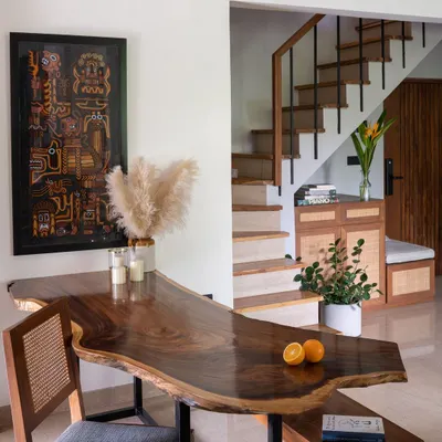 The uniquely shaped live-edge wooden dining table is the heart of our penthouse, 301. Its organic form guides the flow between the living, dining, and staircase areas, tying the open-plan space together.