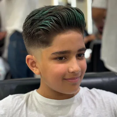 A close-up of a boy's fade haircut with a pop of vibrant green on top. This is a fun and stylish way to experiment with color and stand out from the crowd.