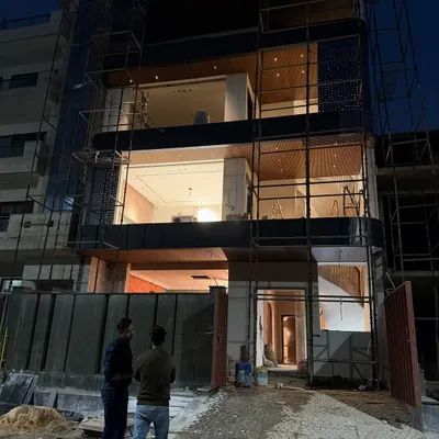 A night view of the independent house in Noida Sector 100. The multi-level lighting design highlights the wooden ceilings and open layout.