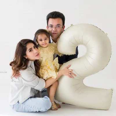 A classic family portrait for a second birthday celebration. The number '2' balloon adds a festive touch to this memory.