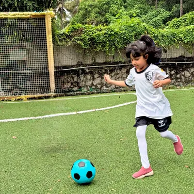 A young girl confidently dribbles the ball towards the goal, embodying the spirit and skill we nurture in our girls' football program.