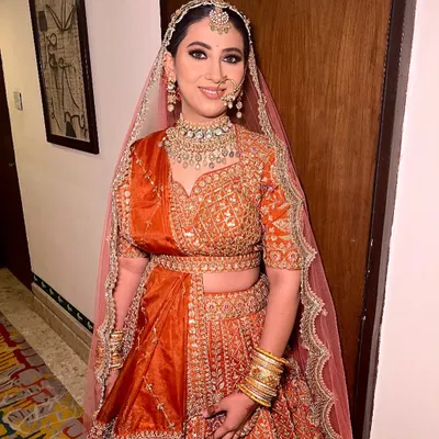 A full view of our magnificent orange bridal lehenga. The detailed embroidery across the entire skirt and the perfectly coordinated dupatta create a truly royal look for your wedding day.