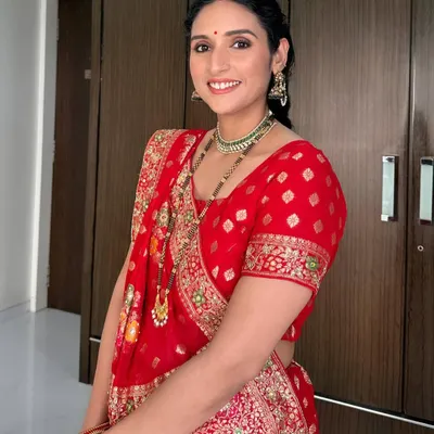 A full-length view of a client ready for Karwachauth. Her soft glam makeup, featuring defined eyes and a radiant base, pairs perfectly with her traditional red bandhani saree.