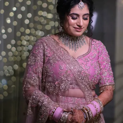 A beautiful bride in her pink lehenga, surrounded by the soft glow of bokeh lights. This portrait captures her serene happiness just before the main event.