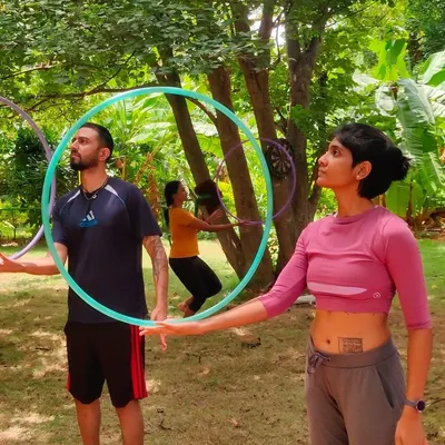 A candid shot of participants learning hoop isolations together outdoors, capturing the hands-on, communal learning experience at a flow fest.