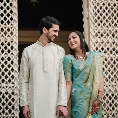 A shared glance filled with love, framed by the intricate details of a traditional haveli doorway. We love using architectural elements to tell a story.