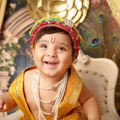 The joyful and mischievous smile of little Krishna is perfectly captured in this close-up. The colorful mukut and pearl necklaces are part of the traditional costume I provide for my Janmashtami themed photoshoots.
