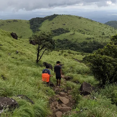 Two trekkers on the trail to Tadiandamol, Coorg's highest peak. The path winds through beautiful green meadows and Shola forests.