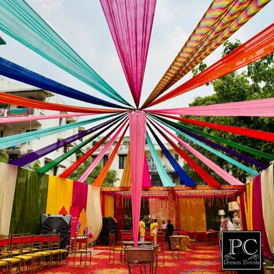 I love creating that perfect, festive 'shadi vala ghar' feel for Haldi and Mehndi functions. This outdoor setup features a canopy of vibrant, multi-colored drapes, creating a joyful and picturesque setting for your pre-wedding rituals.