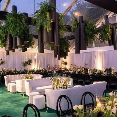 A view of our versatile event space, transformed for a lush green and white themed celebration. The hanging installations and modern lounge furniture showcase the venue's adaptability.