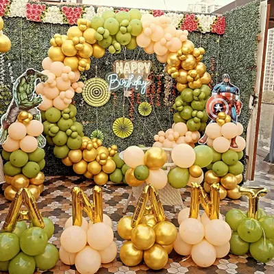 An Avengers-themed birthday party with a full balloon ring against a green wall. This setup includes Hulk and Captain America cutouts and balloon letters spelling out the birthday boy's name.