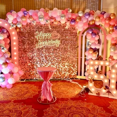 A grand setup for a 50th anniversary party. We used a rose gold sequin wall, illuminated marquee numbers, and elaborate balloon arches in pink and pastel tones to create a festive and elegant photo zone.