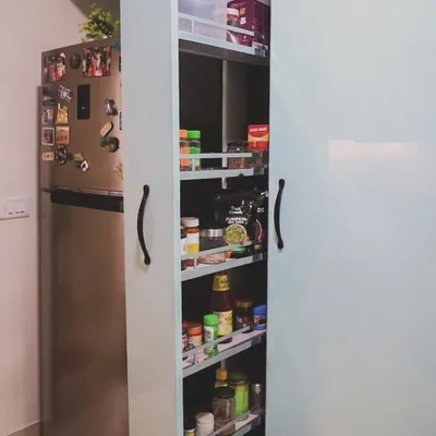 This tall pull-out pantry unit is a perfect example of our smart storage solutions. It utilizes vertical space next to the refrigerator, providing multiple shelves for organizing spices, jars, and packaged goods.