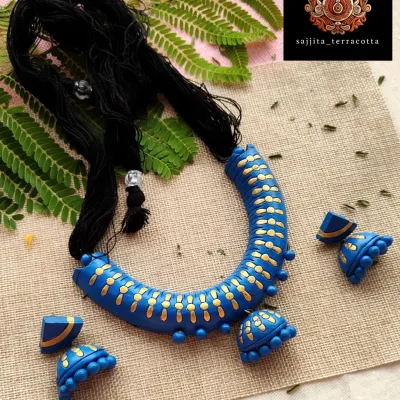 This is my 'hansli' or collar-style necklace, designed to sit elegantly on the neckline for a bold, modern statement. The deep blue is accented with delicate gold patterns, and the set includes a hanging jhumka and matching half-moon earrings.