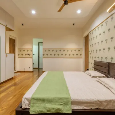 The parents' bedroom at Villa 17, designed for warmth and comfort. The space features a tropical-inspired wallpaper and custom wardrobes with sage green arched panels.