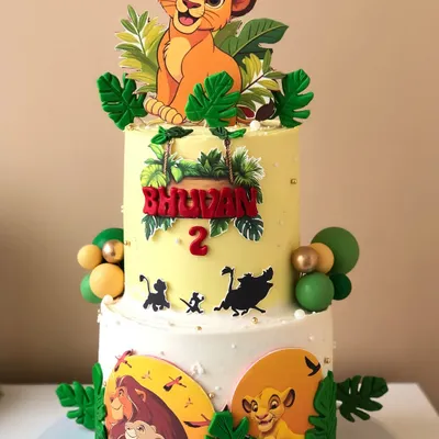 A vibrant two-tiered Lion King cake for a second birthday, featuring Simba and silhouettes of other characters from the movie.