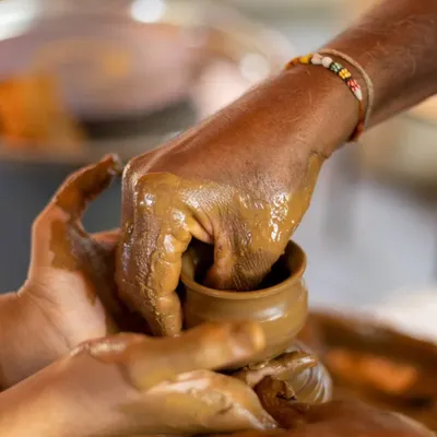 An instructor guides a guest's hands in pottery, a beautiful moment of shared creativity and learning.