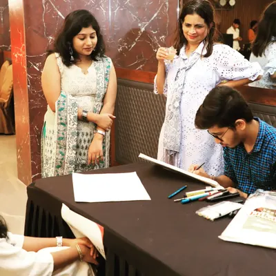 Guests watch as a caricature artist creates a fun, personalized souvenir at a corporate event for Fern Hotels & Resorts. These interactive stations are an excellent way to encourage mingling and provide guests with a unique takeaway.