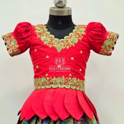 A close-up of a red blouse with stunning green and gold maggam work. This intricate hand embroidery is what makes each piece unique.