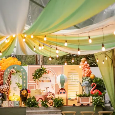 A stunning wide shot of Mireya's boho 'Wild One' party. The setup features a beautiful tent-style draping, a custom-designed backdrop with pastel colors, and a whole crew of friendly jungle animals.