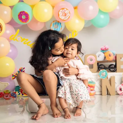 A sweet moment between two sisters during a donut-themed first birthday shoot. We love capturing the natural affection between siblings, from gentle kisses to playful giggles.