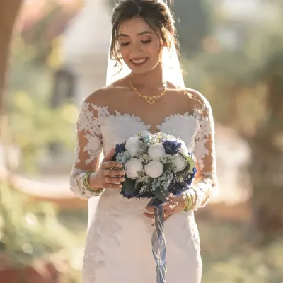 A radiant bride, lost in a happy thought just before the ceremony. The soft, natural light highlights her beautiful smile and the delicate details of her wedding gown.
