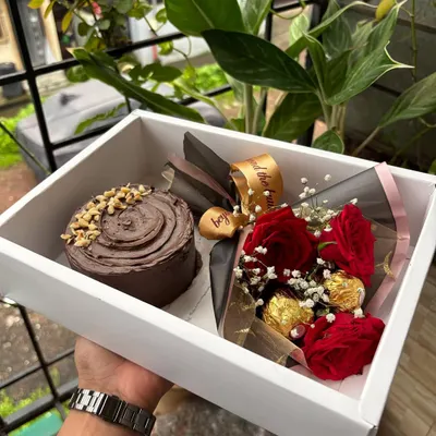 A beautiful gift hamper featuring a mini chocolate cake and a fresh flower bouquet with roses and Ferrero Rocher.