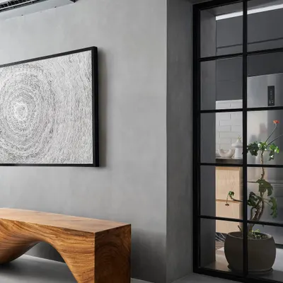 The living room of Zen House features grey micro-concrete floors and walls, which create a seamless, monolithic backdrop. This is balanced by the warmth of a statement wooden bench made from a single piece of East Indian walnut.