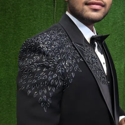 It is all in the details. This close-up shows the hand-embroidered beadwork on one of our signature party wear tuxedos. This level of craftsmanship is what sets our bespoke tailoring apart, adding a touch of luxury and uniqueness to your outfit.