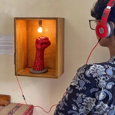 A visitor interacting with the 'Orma Petti' installation. Guests are invited to listen to the memory associated with the object inside, creating a personal and multisensory art experience.